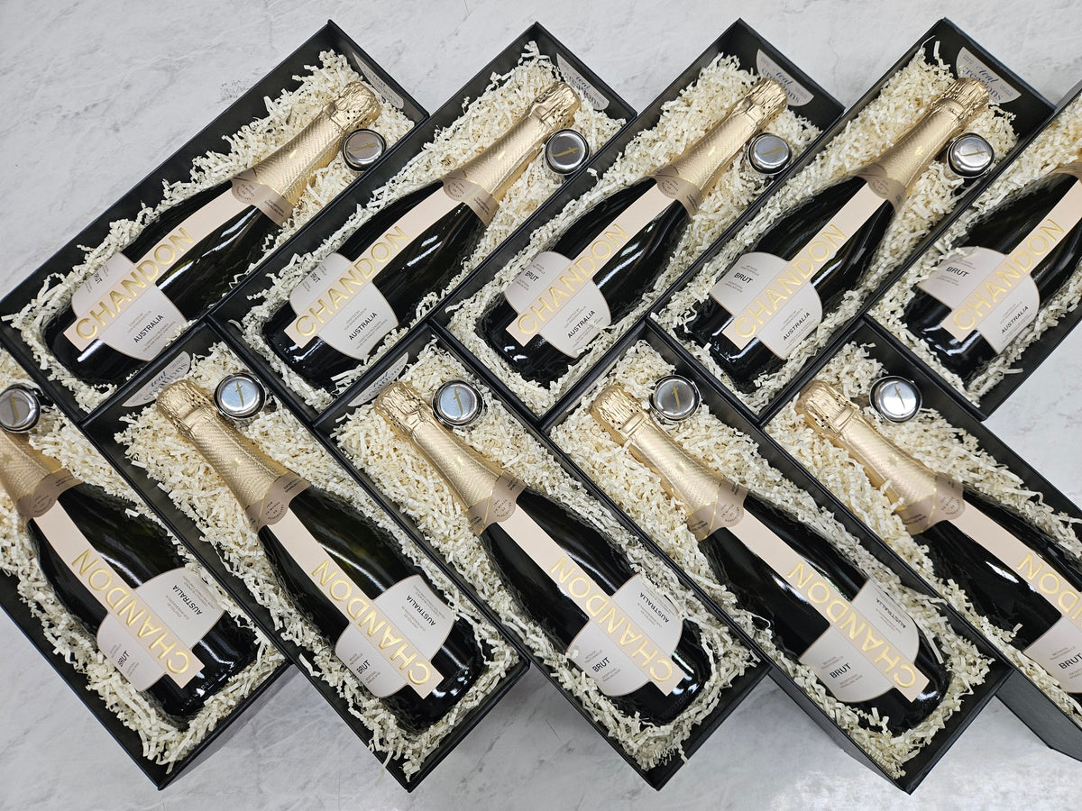Multiple bottles of champagne in gift boxes arranged in a grid on a light background
